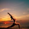 a woman in a bikini doing a yoga pose on the beach